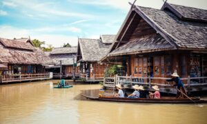 Explore the vibrant and traditional floating market in Thailand, with wooden houses and tourists on boats.